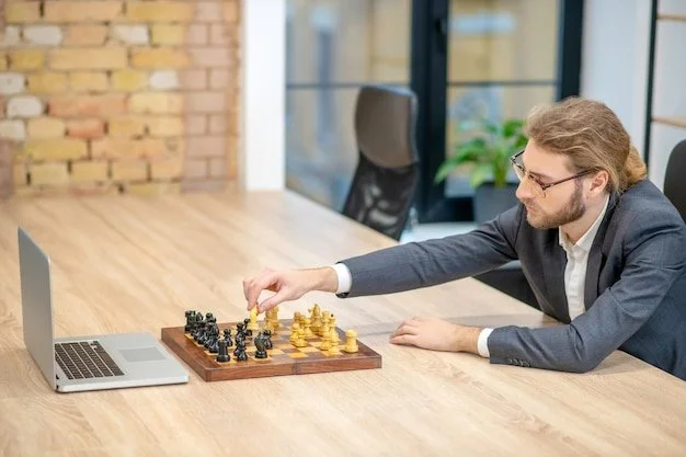 Man in suit and glasses playing chess, moving a white pawn. A laptop is on the table in an office.